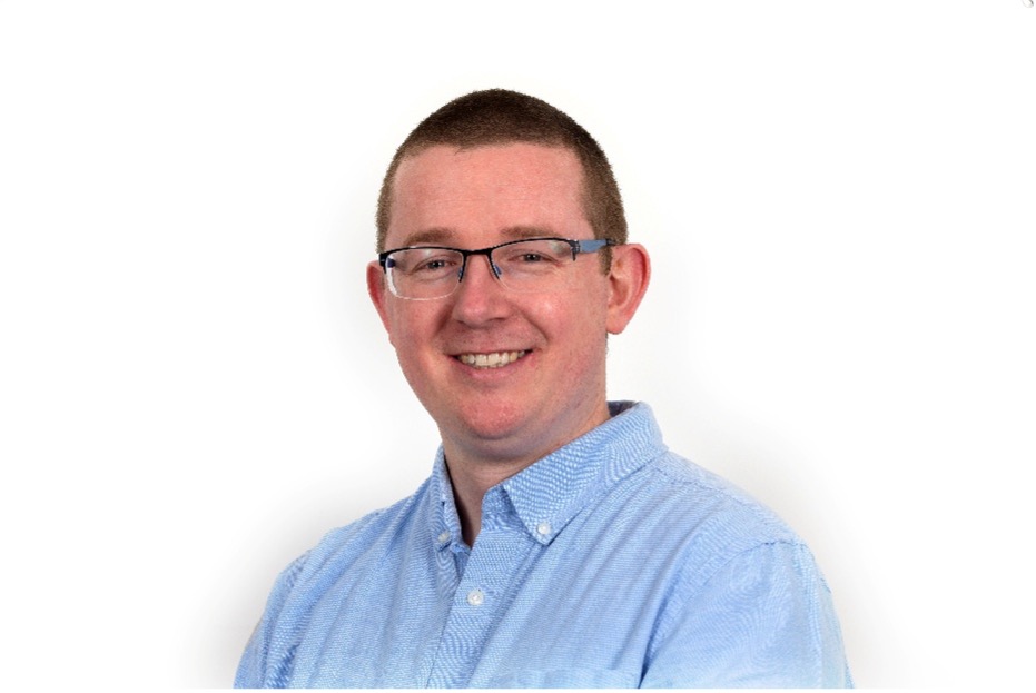 Bust photo of Keith Quille in front of a projection.